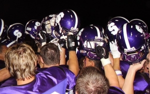 Santana players raise their helmets triumphantly after a 31-20 win over cross-town rival West Hills.